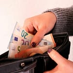 a woman is holding a wallet full of money