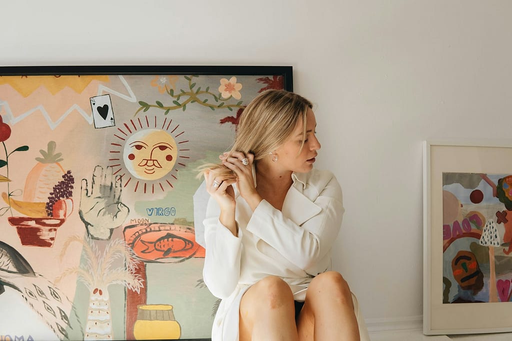 a woman sitting on a chair in front of a painting