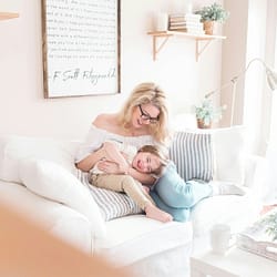 woman and baby sitting on white sofa