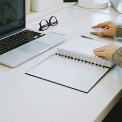 person touching white spiral notebook